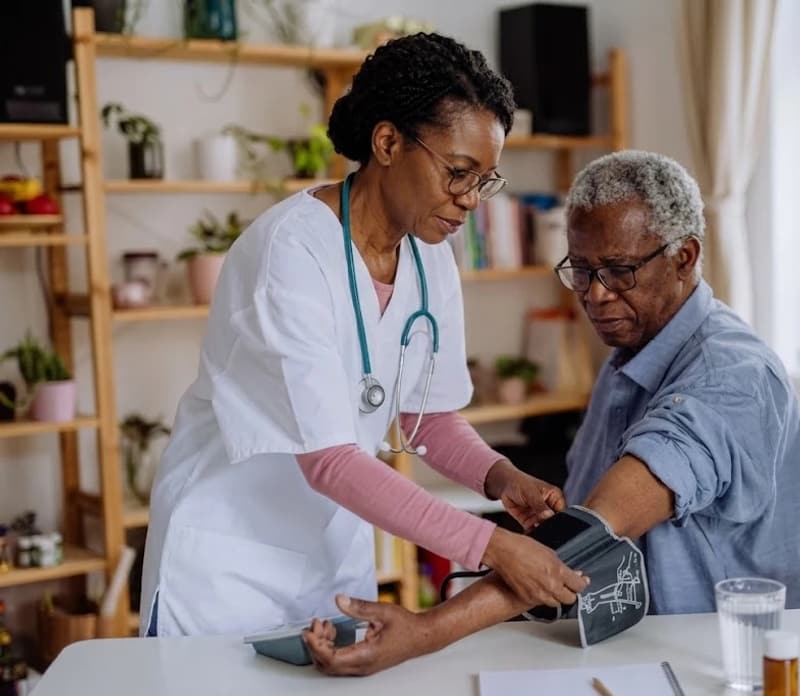 A MooreLife nurse checks an older man’s blood pressure at his dining table